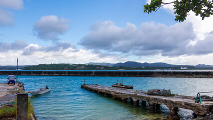 Obraz premium The tranquil scene of Kouri Island's fishing port in Okinawa, with its mottled old piers.