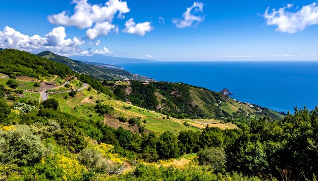 Expansive coastal scene with rolling green hills, winding roads, and a vast blue ocean