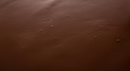 Abstract close-up of a rich, dark brown texture, resembling a smooth melted dessert glaze or confectionery coating, inviting a sense of deliciousness and warmth with its subtle surface details