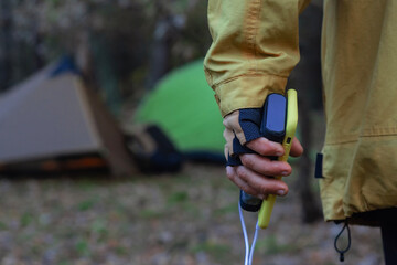 Person charging smartphone with power bank outdoors during camping trip near tent. Concept of mobile energy, off grid power supply, travel technology, emergency charging and adventure lifestyle.