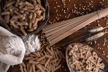 vari tipi di paste integrali con chicchi di grano su un tavolo di legno   © zole4