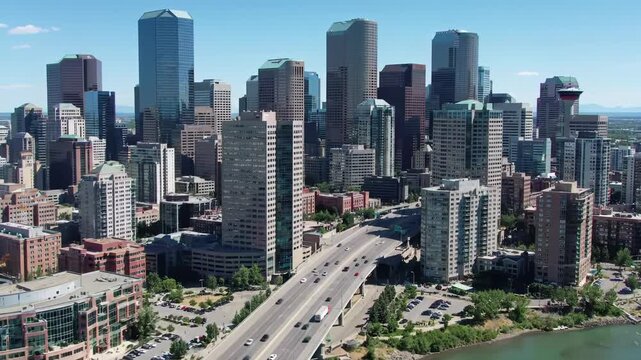 Slow sweeping aerial video of a bustling modern metropolis with gleaming glass, steel skyscrapers, multi-lane highway bridge, fast-moving vehicles, and Calgary Tower. Expansive urban panorama