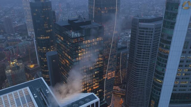Dramatic aerial backwards flight from Omniturm modern office building and banks towers in Frankfurt financial district on a foggy evening