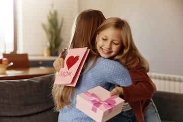 Girl hugging her mom with a handmade card and gift box