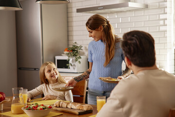 Smiling Mom Serving Breakfast to Family at Kitchen Table