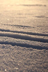 Ski tracks in the snow. White snow-covered ground or surface of a frozen lake. Skier's ski tracks, dents in the snow. Winter background