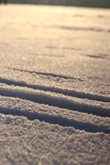 Ski tracks in the snow. White snow-covered ground or surface of a frozen lake. Skier's ski tracks, dents in the snow. Winter background