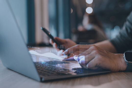 Close-up of man hands using laptop and smartphone with digital business data overlay. Concept of Artificial Intelligence, IoT, and financial technology. - Powered by Adobe