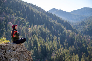 Relaxed woman breathing fresh air in a green pine forest and making breathing exercises 