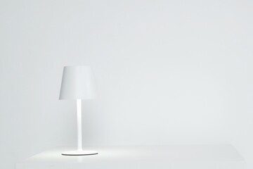 Modern White Conical Table Lamp with Warm Glow.Sleek modern white conical table lamp with warm glow on slim stem, isolated for interior lighting mockups and home decor visuals.