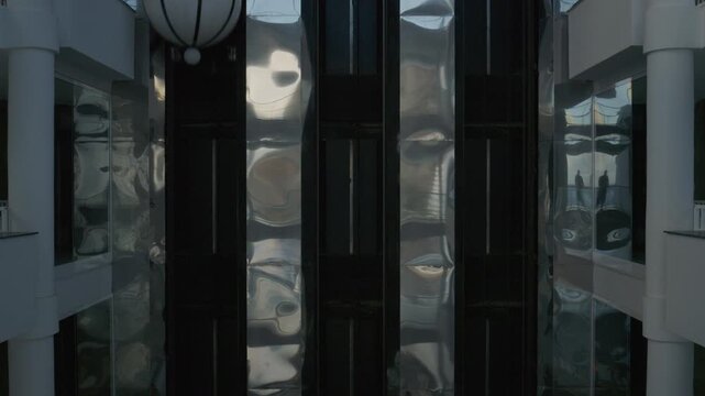 A ride in a modern glass elevator as the camera pans smoothly capturing the elevator's bright interior and elegant design. 