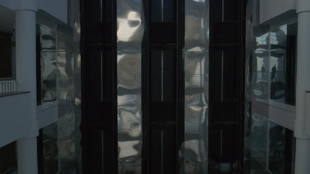 A ride in a modern glass elevator as the camera pans smoothly capturing the elevator's bright interior and elegant design. 