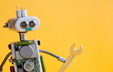 Robot mechanic serviceman handyman electrician worker with hand wrench. Funny toy close-up. yellow...