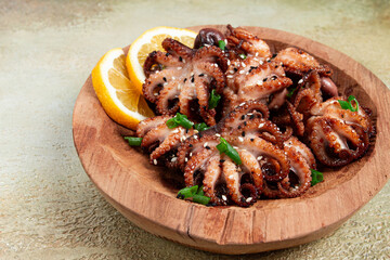 grilled baby octopus with green onions, lemon slices, on a wooden plate, homemade, no people, © Gala_Didebashvili
