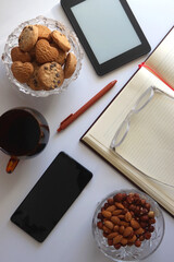 Notebook, pen, tablet, phone, coffee and snacks on white background. Top view. 