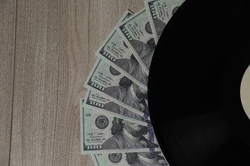 Money arranged with a vinyl record on a wooden surface highlighting a creative juxtaposition of...