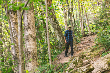 African American man hikes peacefully through the forest and trees in nature on a trail up a mountain in Vermont, New England, USA