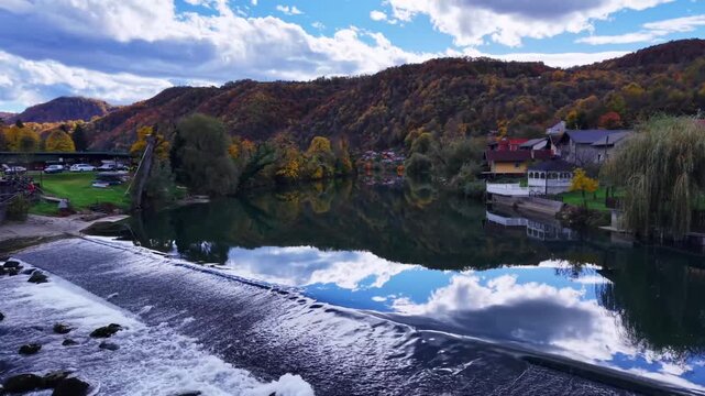 Scenic riverside view with weir and colorful autumn frest reflection