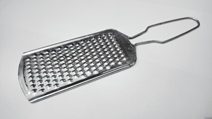 Manual stainless steel cheese grater tool isolated on white. Handheld metal shredder for future culinary success and food prep. © Muhammad Nashieh