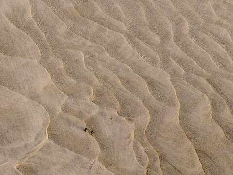 Aerial view of rippled sand forming wave-like patterns, the textures catch the sunlight, creating an interplay of light and shadow, Manikganj, Bangladesh.