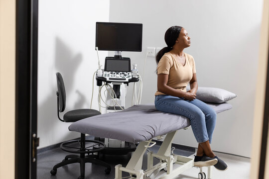 Medical examination table sitting on vinyl floor in clinic, ultrasound machine and probes nearby