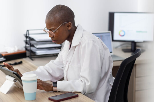 Tablet is displaying chart on small stand atop wooden desk in clinic office, with coffee cup