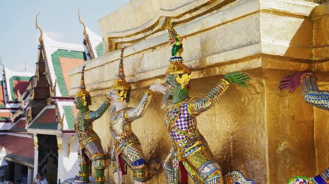 Colorful statues of yaksha demon guardians support golden chedi at Wat Phra Kaew, located within the Grand Palace in Bangkok