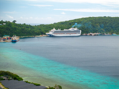 Aerial view of a colossal cruise ship docked at the harbor, contrasting with the vibrant turquoise waters and lush green hills, Port Vila, Shefa Province, Vanuatu.