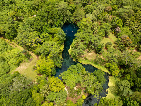 Aerial view of the Blue Hole's crystalline waters winding through a vibrant tapestry of lush, emerald rainforest, Espirito Santo, Vanuatu.