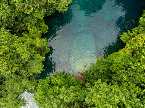 Aerial view of a mesmerizing blue hole surrounded by lush green trees, Espirito Santo, Sanma Province, Vanuatu.