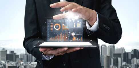 A businessman in a formal suit holds a tablet that displays vibrant data visualizations against a city skyline, representing modern analytics and business innovation. Scalp