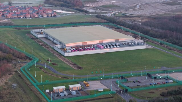 Aerial view of the sprawling Lloyds Horizon Data Centre, a stark contrast of industrial grey against the lush green fields surrounding it, Corby, United Kingdom.
