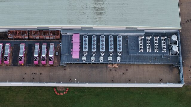 Aerial view of the data center's roof and cooling systems, a symphony of industrial machinery and pink accents against a backdrop of green grass, Corby, United Kingdom.