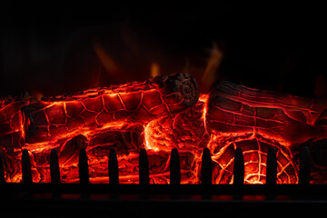 Glowing firewood burning in a fireplace with red hot embers