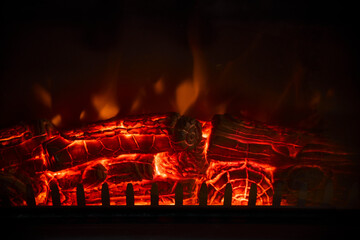 Glowing firewood burning in a fireplace with red hot embers