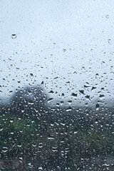 Raindrops on window with blurred landscape on a cloudy day