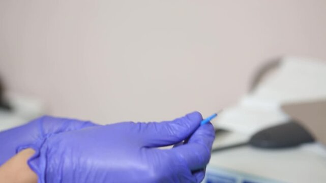 Close up of doctor hands in blue gloves holding loop electrode for electrosurgery. Medical professional preparing equipment for radio wave surgery or coagulation in a clinic.

