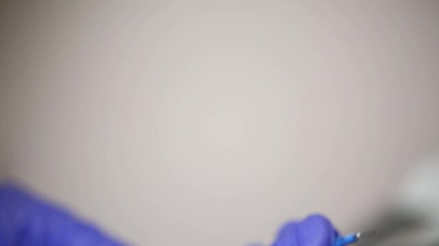 Close up of doctor hands in blue gloves holding loop electrode for electrosurgery. Medical professional preparing equipment for radio wave surgery or coagulation in a clinic.

