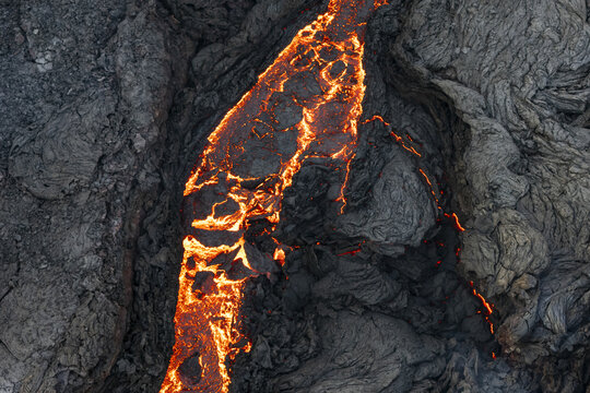 Aerial view of molten rock and magma snake through the cooled, jagged terrain of the Sundhnukur Eruption, Reykjavik, Reykjanes, Iceland.