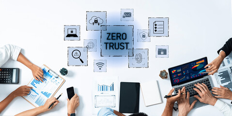 A diverse team collaborates over modern devices, emphasizing the zero trust security approach. Digital graphs and charts highlight data analysis in a professional workspace. Trope