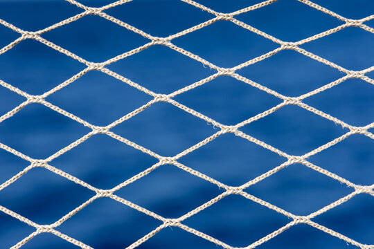 Gros plan sur un filet de protection type bastingage de bateau avec du soleil qui l'&eacute;claire.