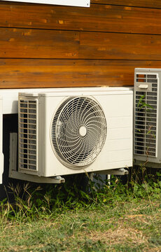 Une pompe &agrave; chaleur install&eacute;e pr&egrave;s d'une maison en bois.