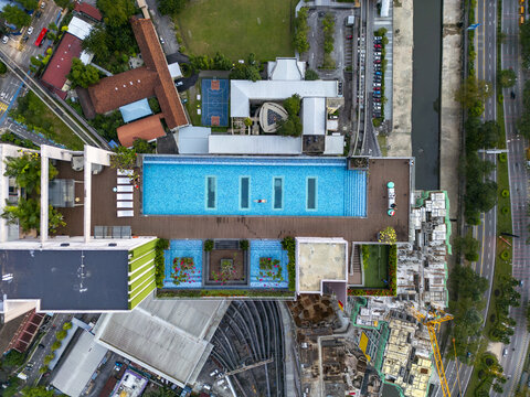 Aerial view of a rooftop pool reflecting the sky, amidst the urban tapestry of buildings and roads, a modern oasis, Kuala Lumpur, Federal Territory of Kuala Lumpur, Malaysia.