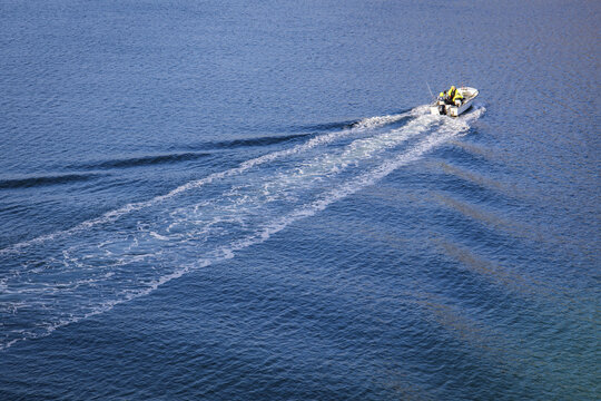 Aerial view of a boat moving across the water, leaving a white trail in its wake, Henningsvaer, Nordland, Norway.