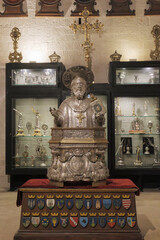 Bari, Italy. Side chapel inside the Basilica of San Nicola featuring a silver bust of St. Nicholas, ornate reliquaries and sacred objects displayed in illuminated cases.