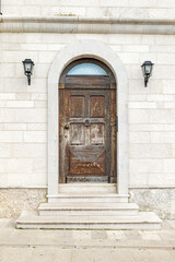 Bari, Italy. Stone facade along Via Venezia in Bari featuring an arched wooden door, weathered textures and wall lamps, reflecting the historic character of the old coastal city.