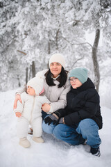 Obraz premium Mother and children enjoying snowy winter forest together