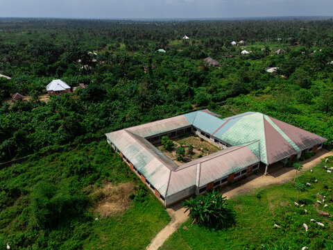 Aerial view of a sprawling building nestled amongst a sea of verdant trees and vegetation, its roof reflecting the sky, Eberi, Rivers, Nigeria.
