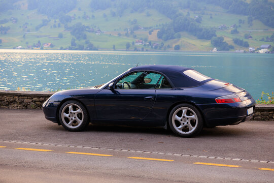 Arth, Switzerland - July 5, 2025: Blue Porsche 911 convertible next to Lake Zug (Zugersee) in canton of Schwyz in Switzerland