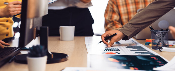 A diverse business team collaborates in a modern office setting, analyzing charts and graphs for marketing strategy. Focused discussions drive productivity and innovation. SACTR